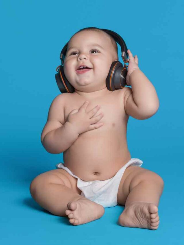 Bebê com expressão de felicidade usando fones de ouvido enquanto escuta música, transmitindo alegria e encantamento ao interagir com os sons. Fundo azul sólido.
