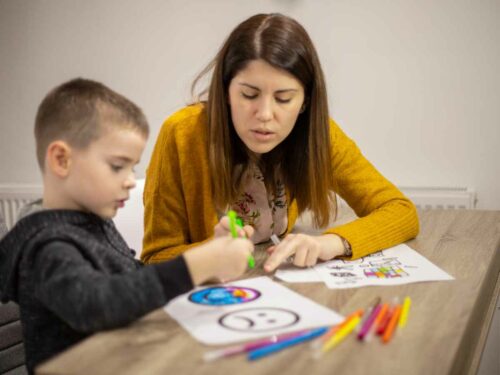 Mãe auxiliando seu filho com atraso no desenvolvimento cognitivo em uma atividade educativa, acompanhando atentamente cada passo para observar sua evolução e oferecer o apoio necessário com carinho e paciência.