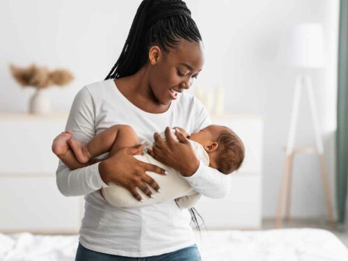 Mãe cantando suavemente para seu filho enquanto o segura no colo e o nina com carinho, criando um momento de aconchego, conexão emocional e tranquilidade entre mãe e bebê.