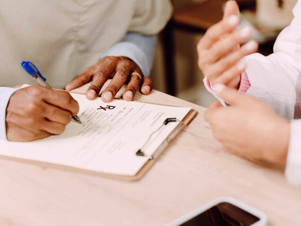 Pai conversando com uma médica enquanto preenche uma ficha com as informações de seu filho, buscando compreender as causas do atraso em seu desenvolvimento.