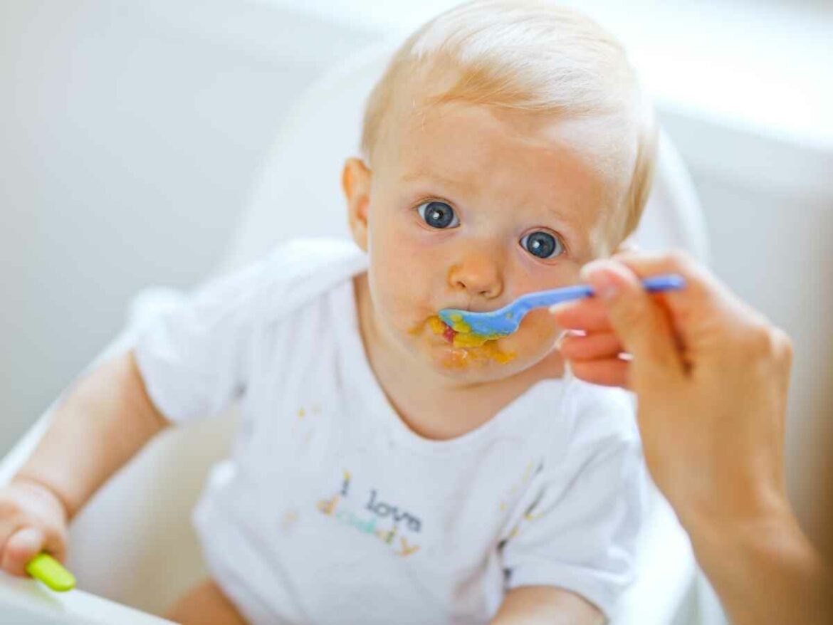 Bebê comendo pamonha em seu cadeirão.