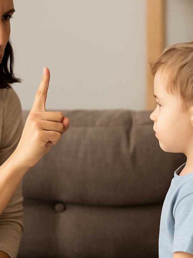 Mulher com expressão séria e dedo em riste repreendendo uma criança pequena. A cena sugere um momento de correção de comportamento.