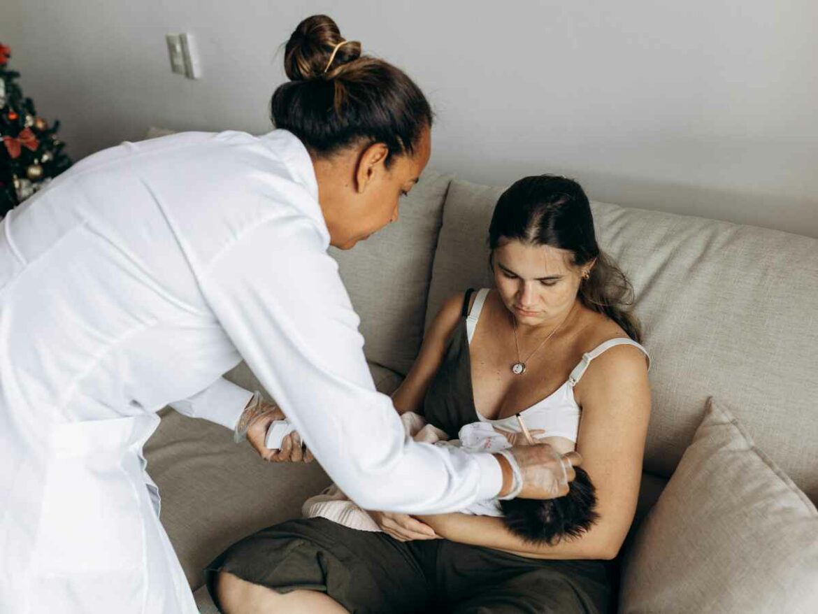 Mãe segura o bebê no colo enquanto pediatra administra medicação, após a criança apresentar resistência em tomar o remédio.