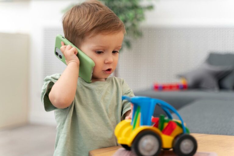 Bebê brincando que está falando por ligação no celular.