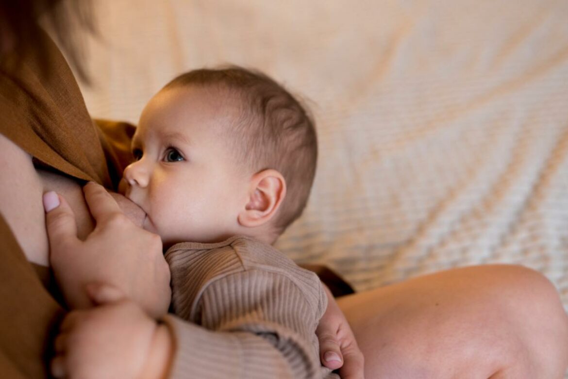 Bebê mamando no colo da mãe. 