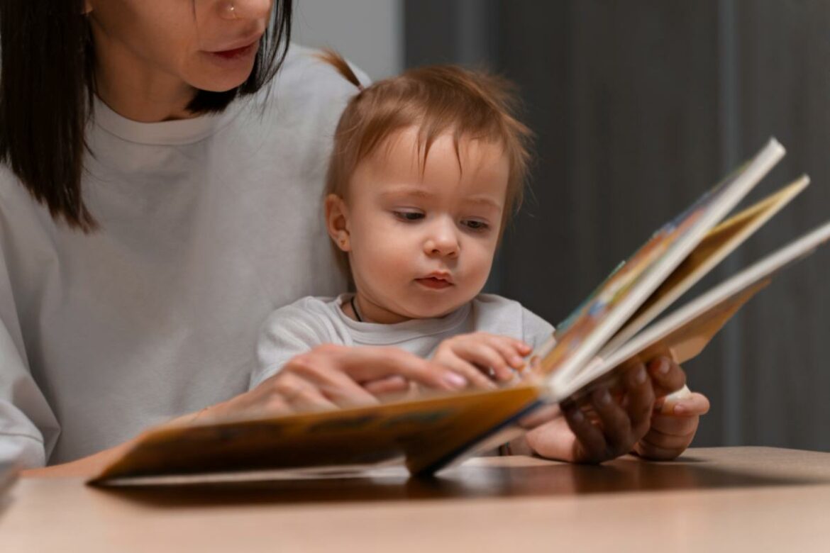 Mãe com a bebê no colo lendo um livro para ela.