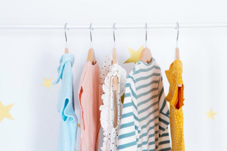 Roupas de bebê pendurada por cabide em uma arara.