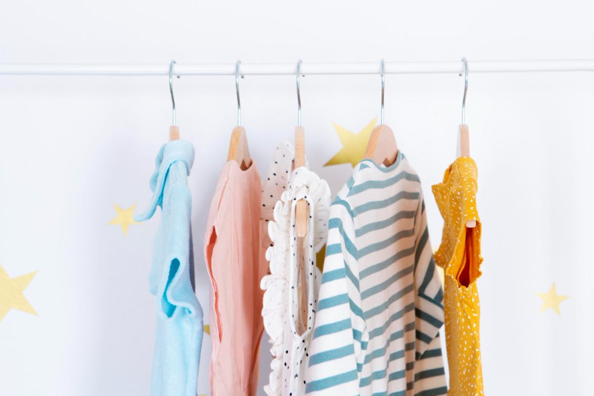 Roupas de bebê pendurada por cabide em uma arara.