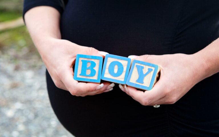 Mãe de menino segurando placa que diz boy.