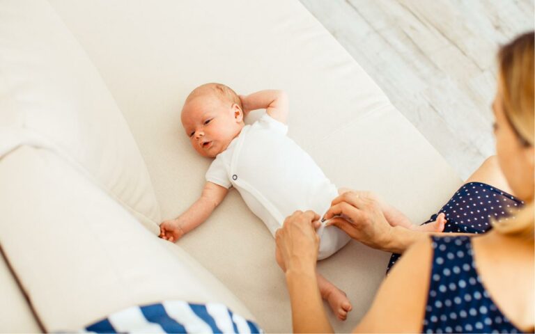 Mãe vestindo bebê de dois meses conforme a estação.