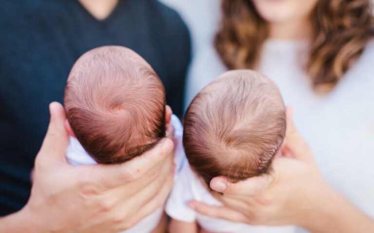 pais segurando bebês gêmeos no colo