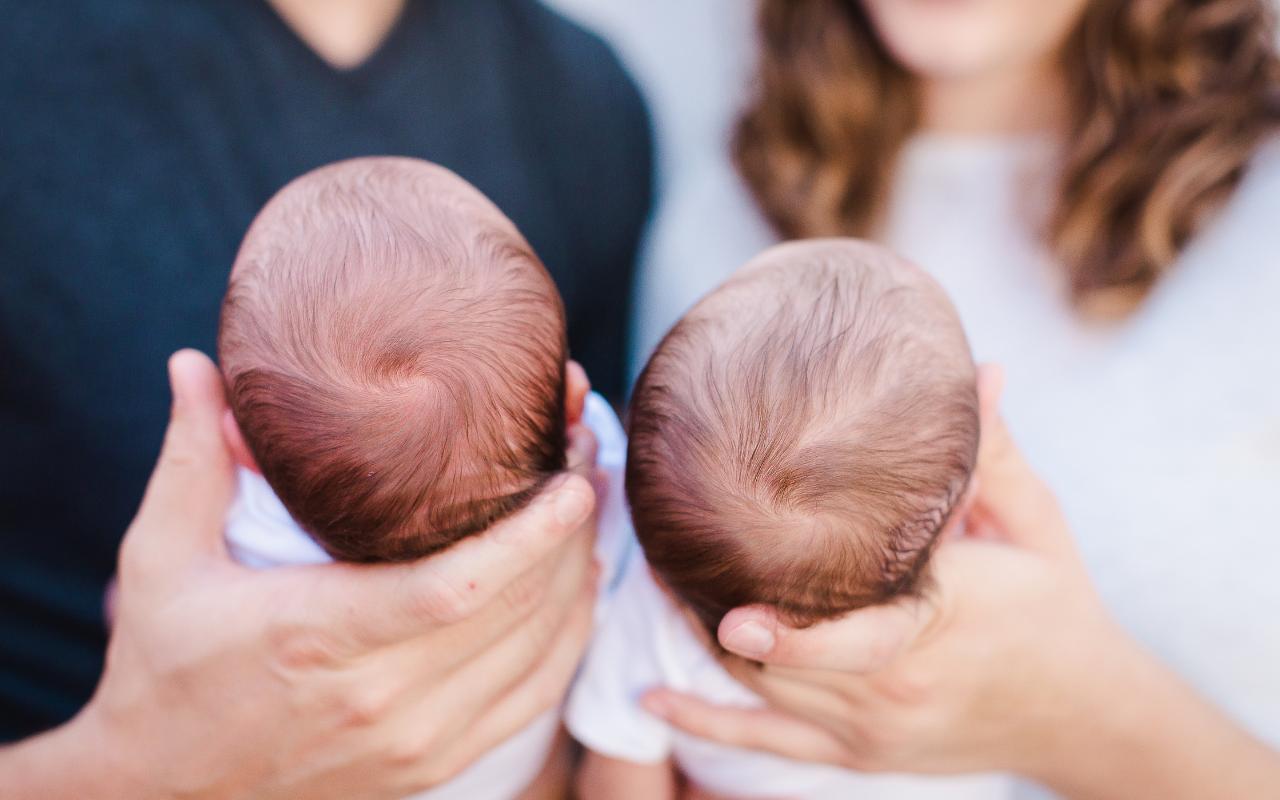 pais segurando bebês gêmeos no colo
