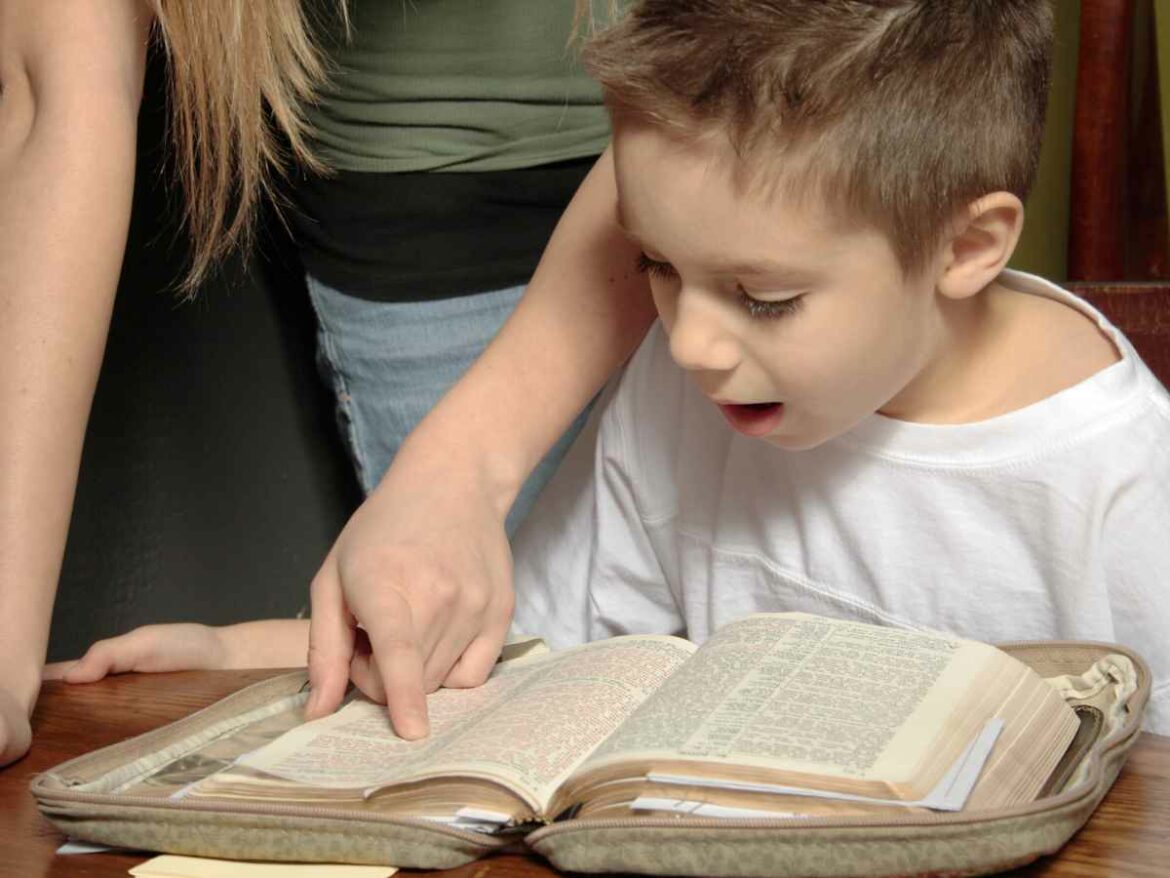 Criança acompanhando a leitura da biblia enquanto um adulto aponta o texto