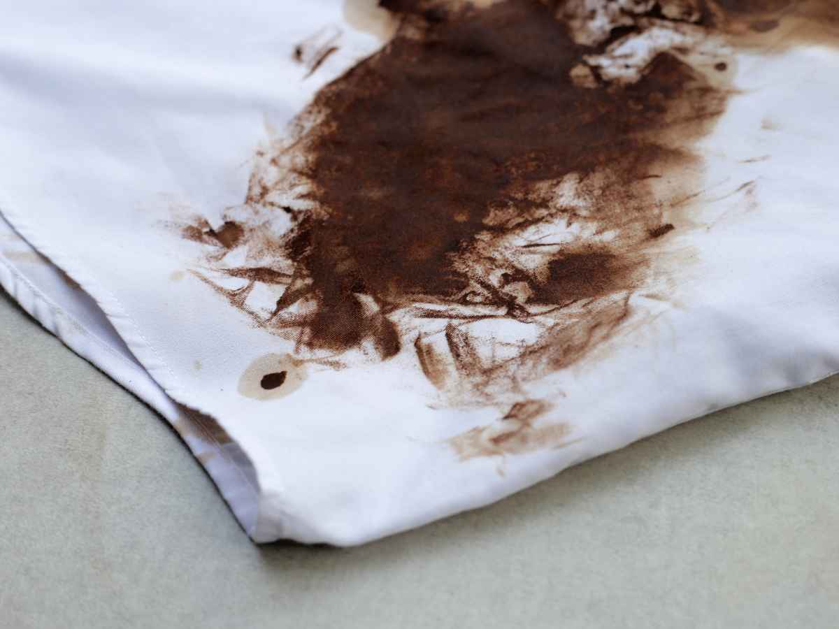 Peça de roupa branca com mancha marrom escura