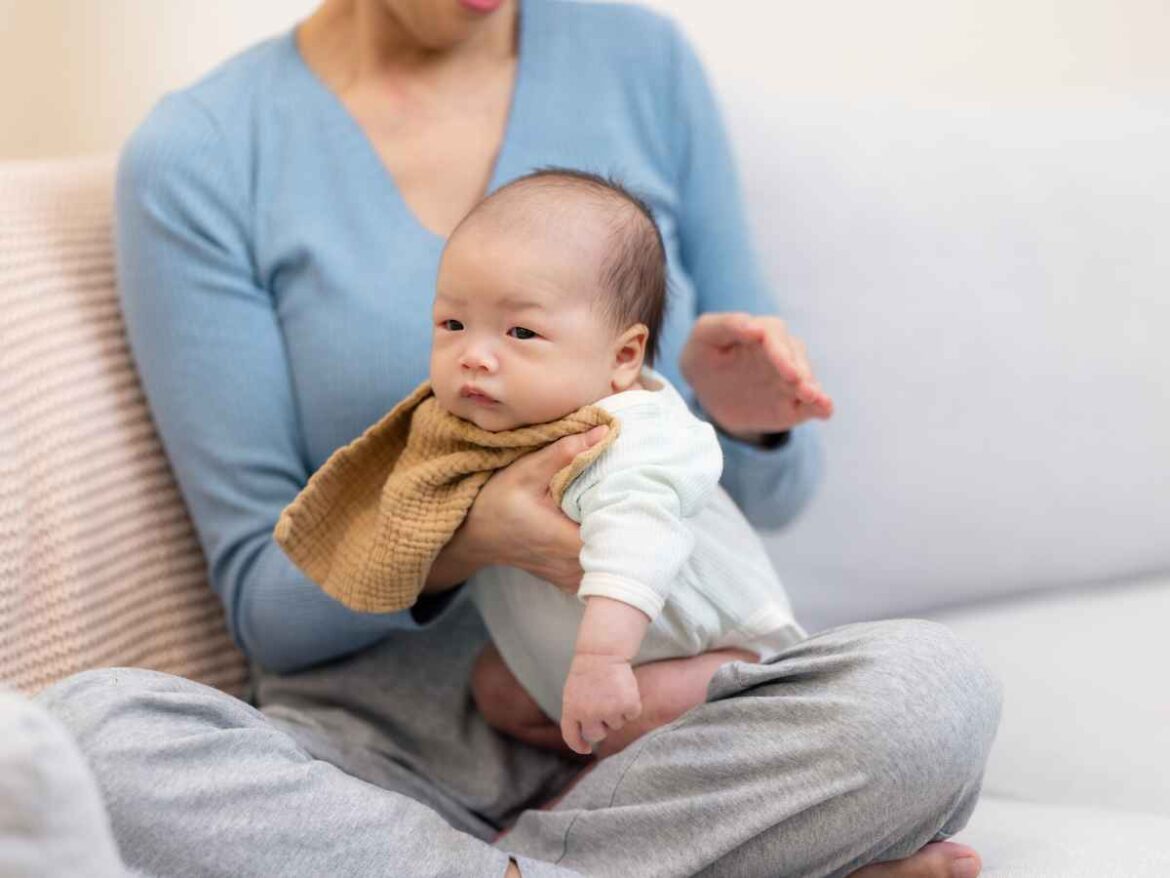 Bebê em posição vertical no colo de sua mãe, essa posição é usada para diminuir o refluxo
