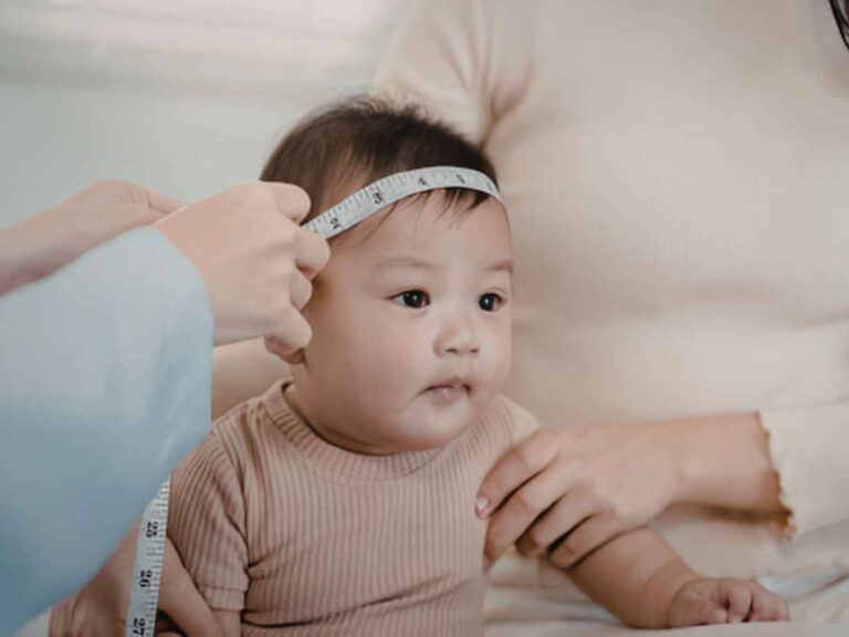Bebê tendo a cabeça medida por uma fita métrica