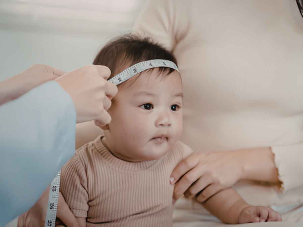 Bebê tendo a cabeça medida por uma fita métrica