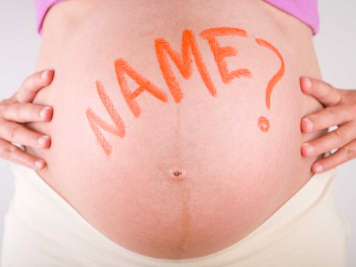 Barriga de gestante com a palavra “name?” escrita, simbolizando a dúvida e o momento de decidir o nome do bebê durante a gravidez.